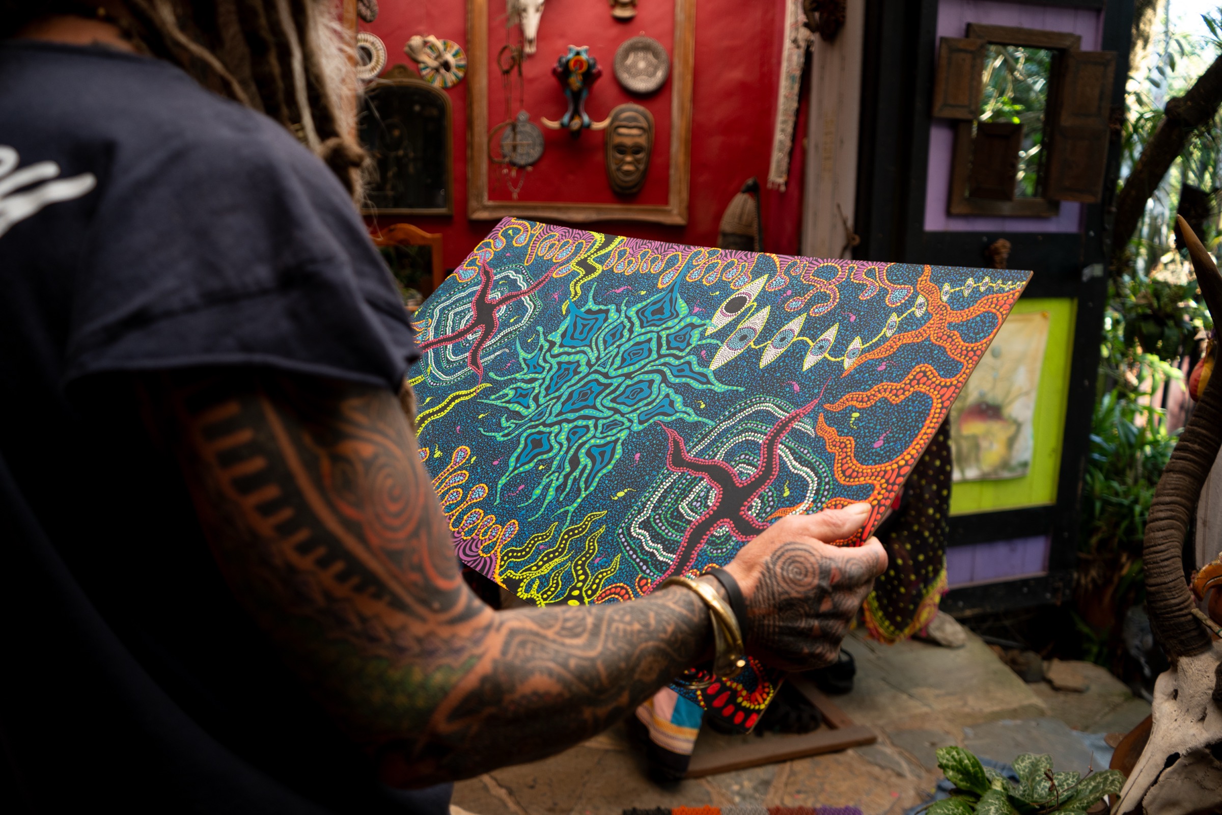 James Liebenberg holding a freshly painted dot artwork in his studio